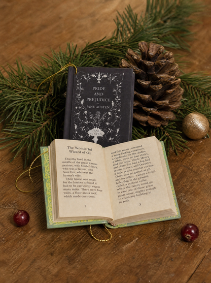 A mini book lying open showing real printed pages, with a second book propped behind it